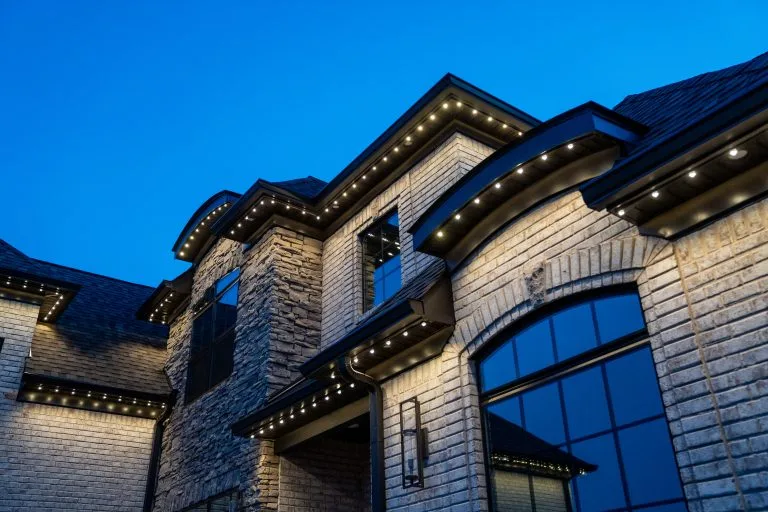 Illuminated architectural features of a luxurious home stand out against a twilight sky