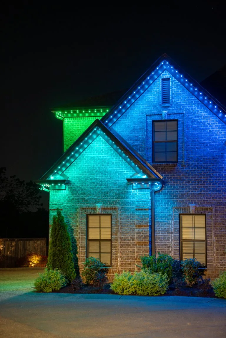 A house is illuminated with vibrant blue and green decorative lights at night