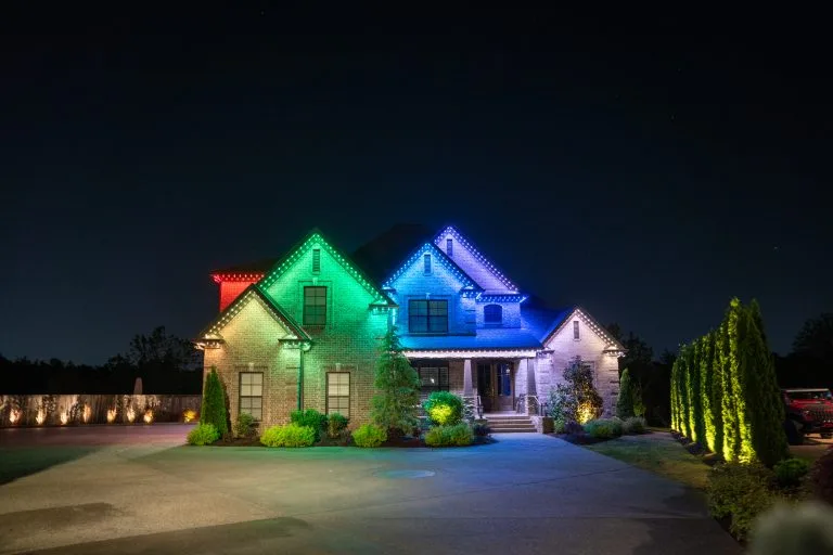 A beautifully lit house displays vibrant colored lights against a night sky