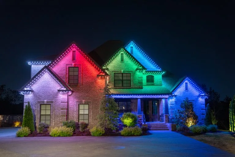 A beautifully lit house features colorful illumination outlining its architectural details at night