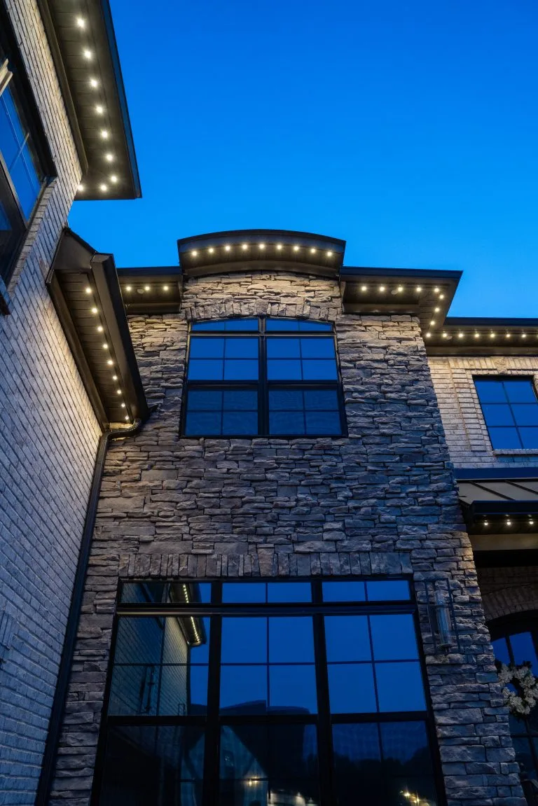 Twinkling lights illuminate a modern home against a twilight sky