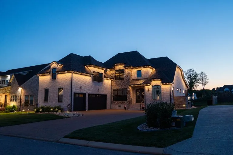 A beautifully illuminated house stands prominently under a deep blue evening sky