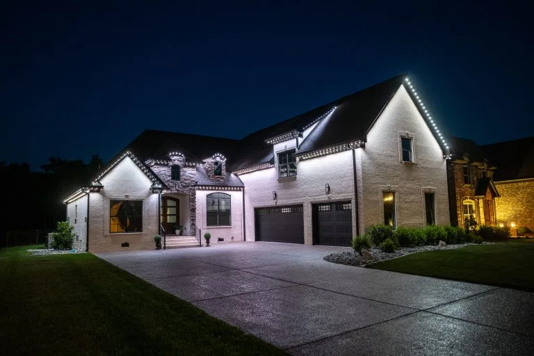 A beautifully illuminated house at night, showcasing elegant exterior lighting and well-maintained landscaping