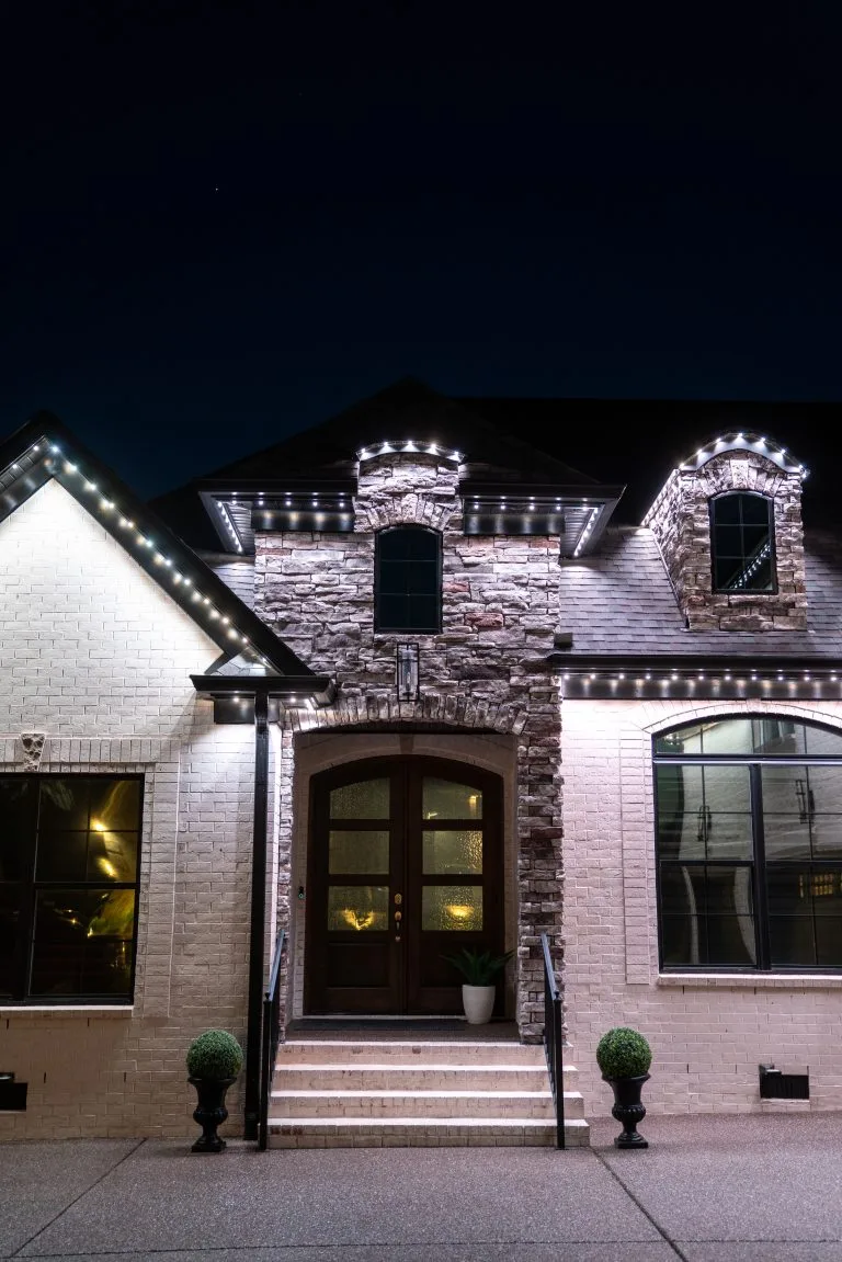 A beautifully lit house features decorative lights outlining its architecture at night