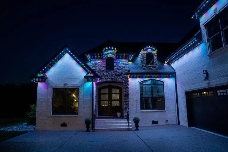 A beautifully lit house glows in colorful lights against a dark night sky