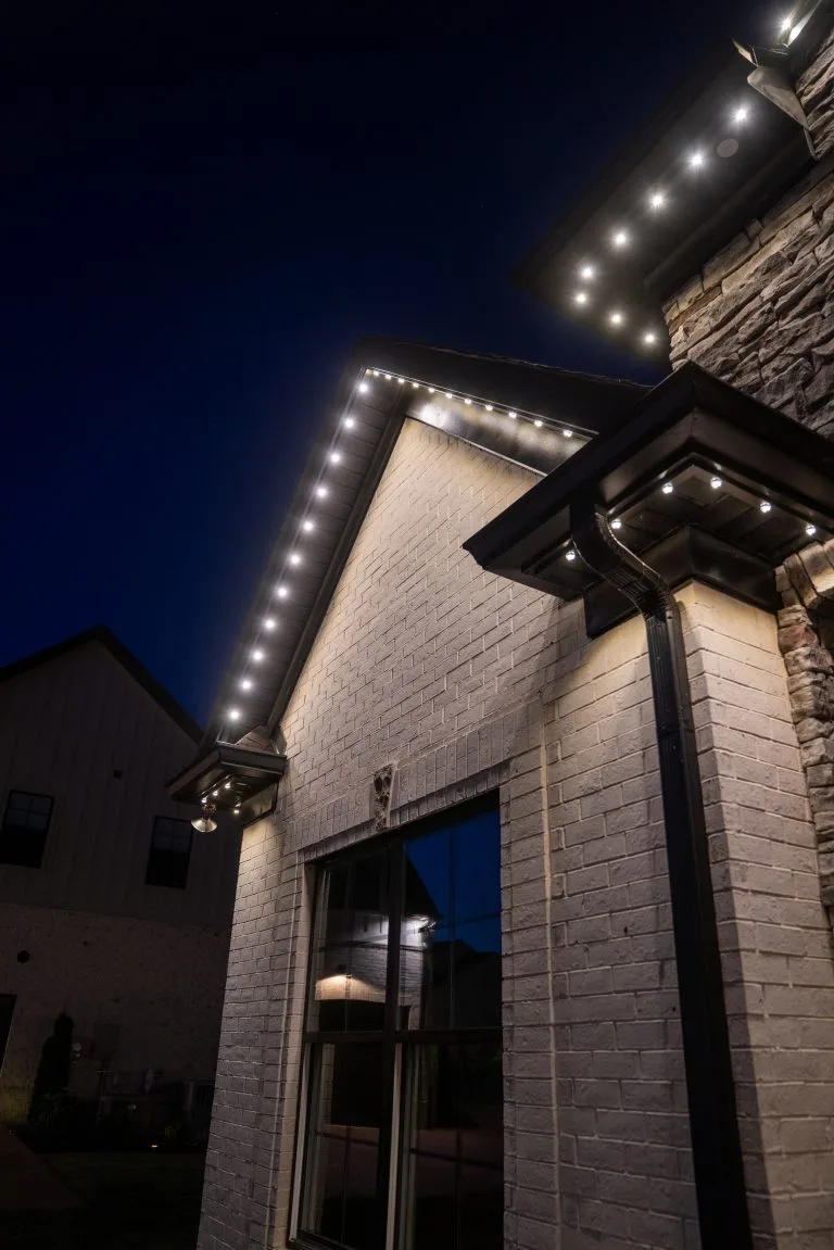 A stylish house glows with decorative lights against a darkening sky