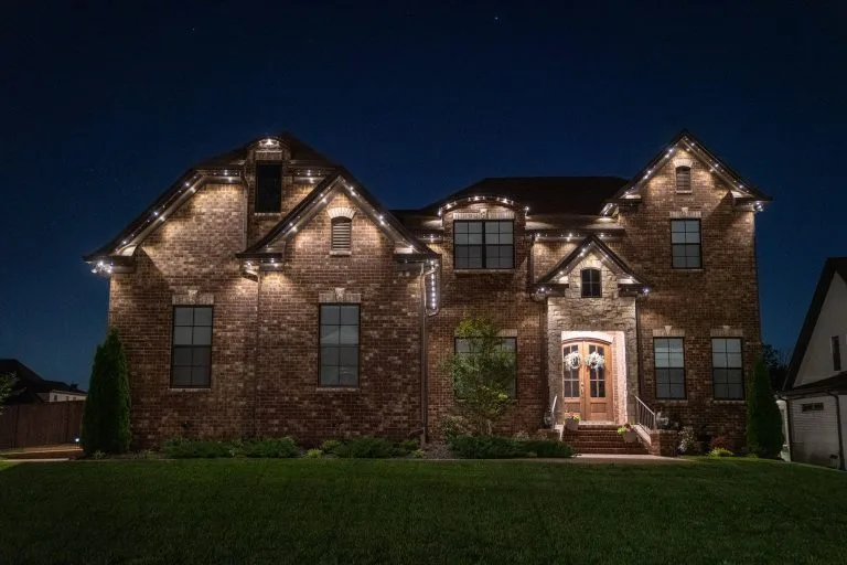 A beautifully lit brick house stands majestically under a night sky