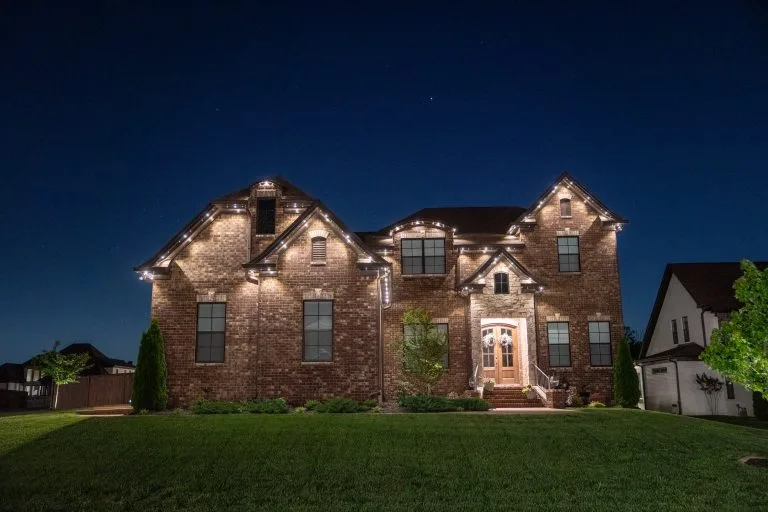 A beautifully lit brick house stands out against a twilight sky