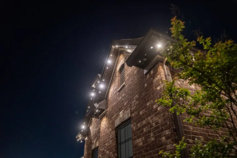 Warm lights illuminate the rooftop of a brick building against a dark sky