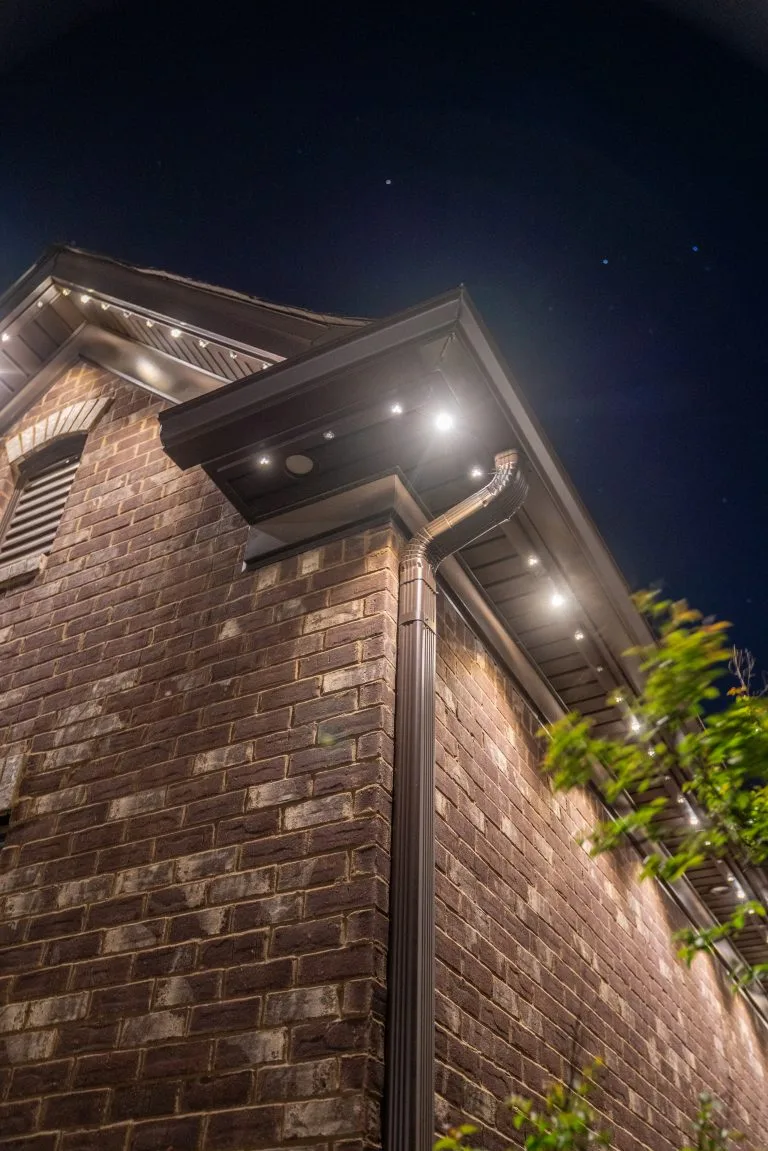 Soft lights illuminate the corner of a brick building against a night sky