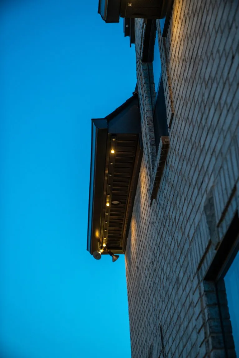 A building's edge is illuminated against a deep blue evening sky