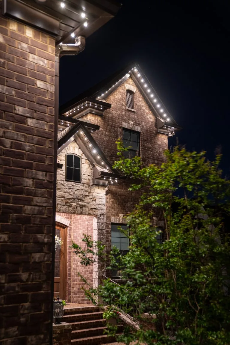 A beautifully lit brick house glows warmly against the night sky