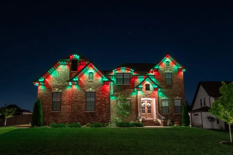A beautifully decorated house shines with red and green lights at night