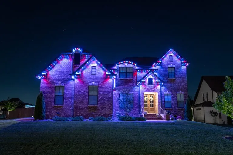 A beautifully decorated house illuminated with vibrant blue and white lights at night