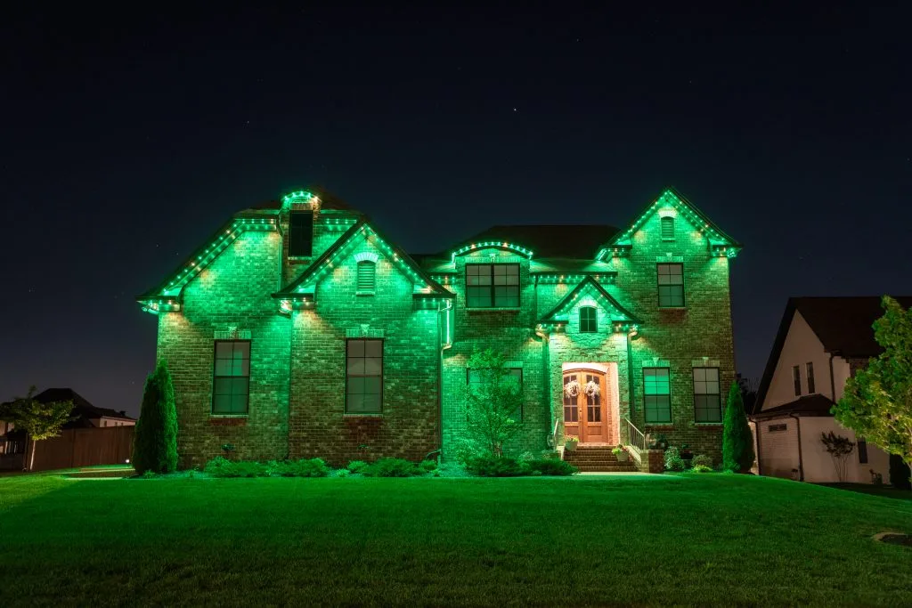 A brick house is beautifully illuminated with vibrant green lights at night