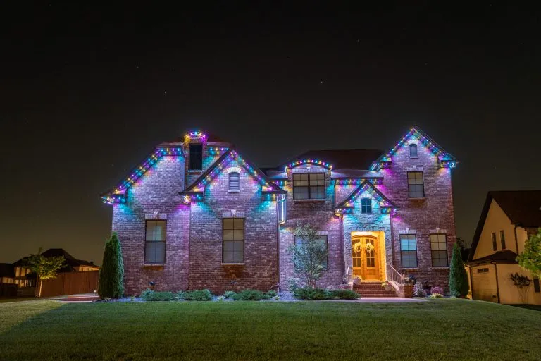 A beautifully lit house adorned with colorful holiday lights shines brightly against a dark sky