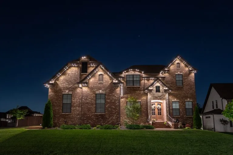 A beautifully illuminated brick house stands against a dark evening sky