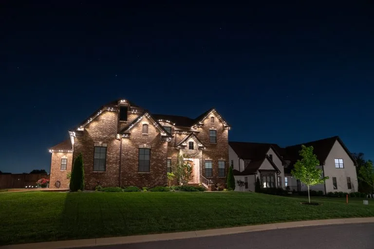 A beautifully lit brick house glows against a darkening sky at night