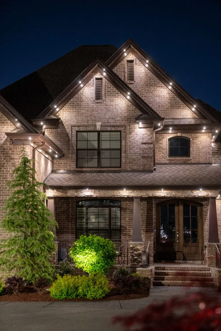 A beautifully illuminated brick house showcases elegant architecture under a night sky