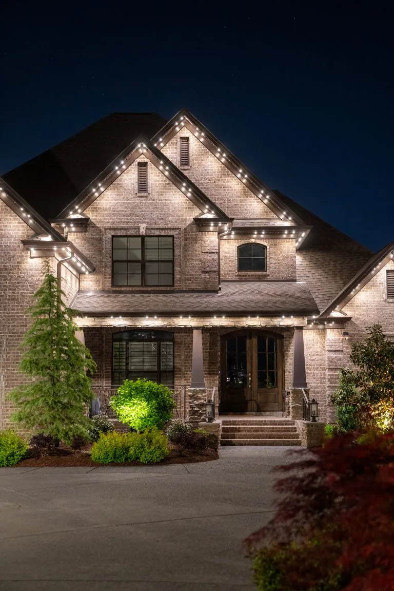 A beautifully lit brick house stands elegantly under the night sky