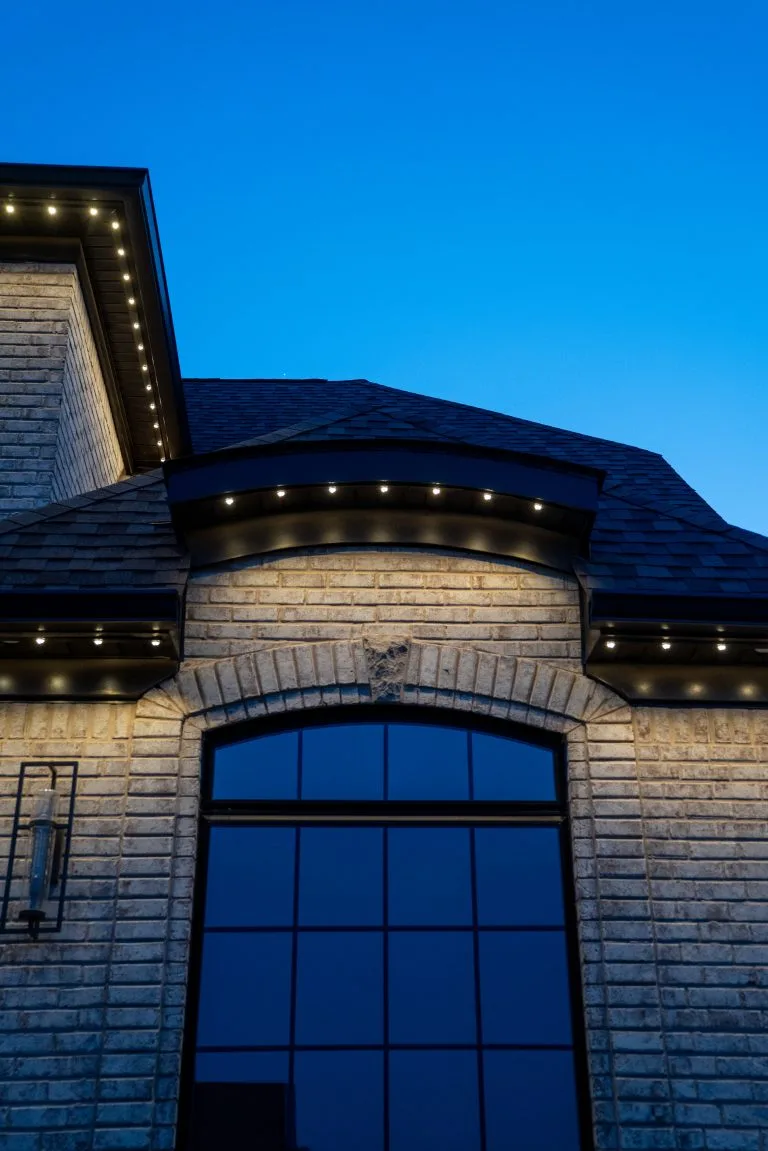 Twilight hues illuminate a brick house adorned with subtle outdoor lighting