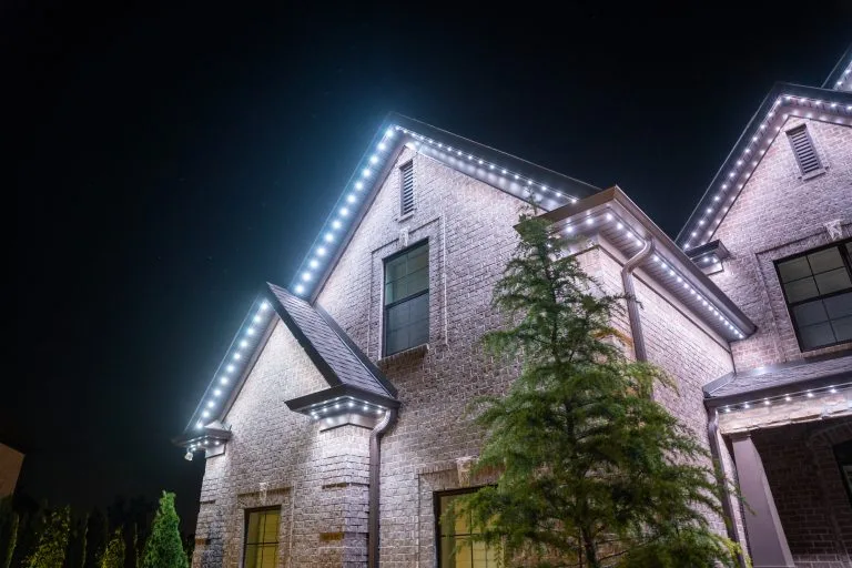 A beautifully illuminated house glows with decorative lights against a dark night sky