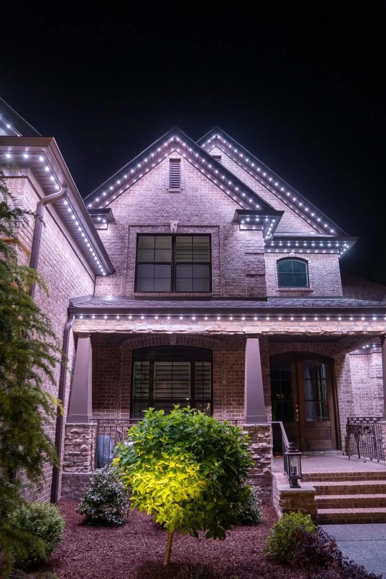 A beautifully illuminated house features decorative lights outlining its architecture