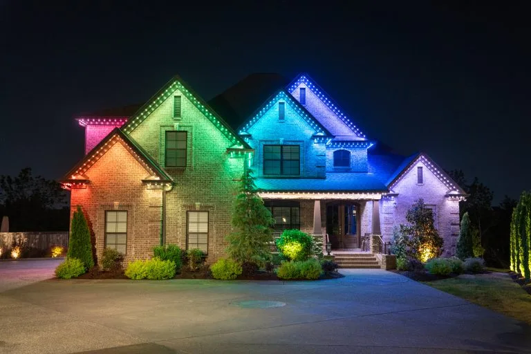 A beautifully illuminated house shines with vibrant, colorful lights at night