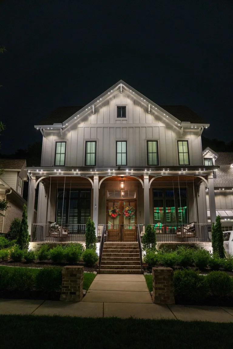 A beautifully lit house features elegant decorations and a welcoming front porch