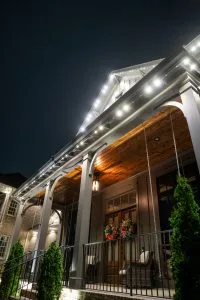 A beautifully lit house at night, featuring elegant architectural details and greenery
