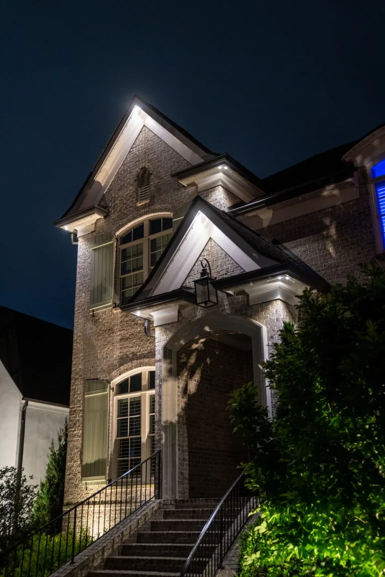 A beautifully lit brick house stands elegantly under a nighttime sky