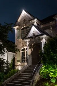 A beautifully illuminated house at night casts a warm glow on its surroundings