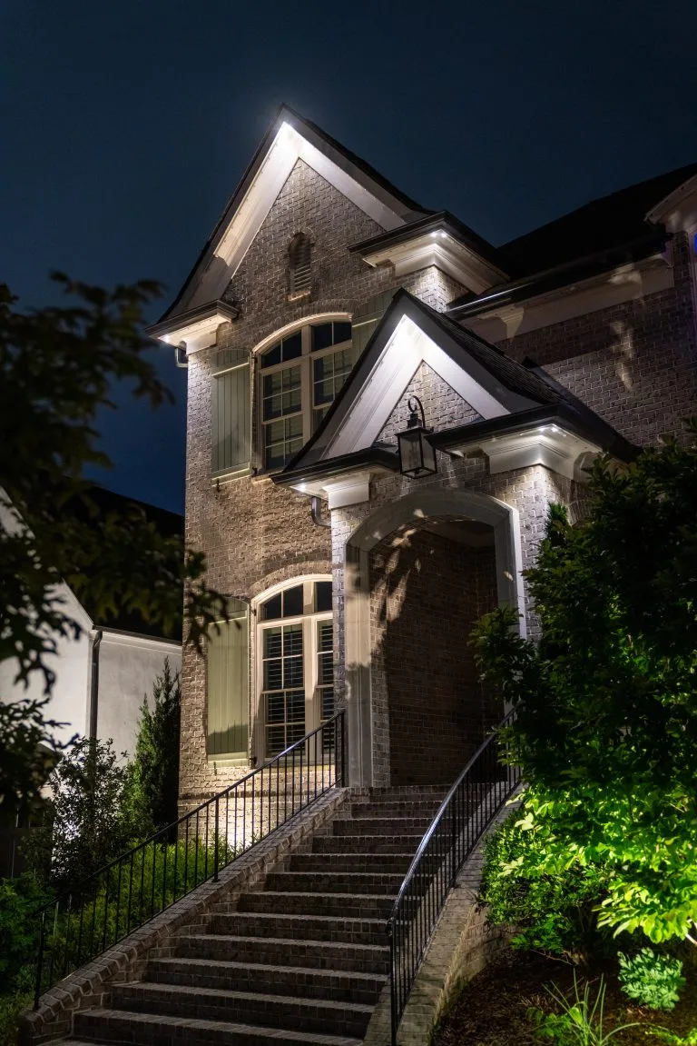 A beautifully illuminated house at night casts a warm glow on its surroundings