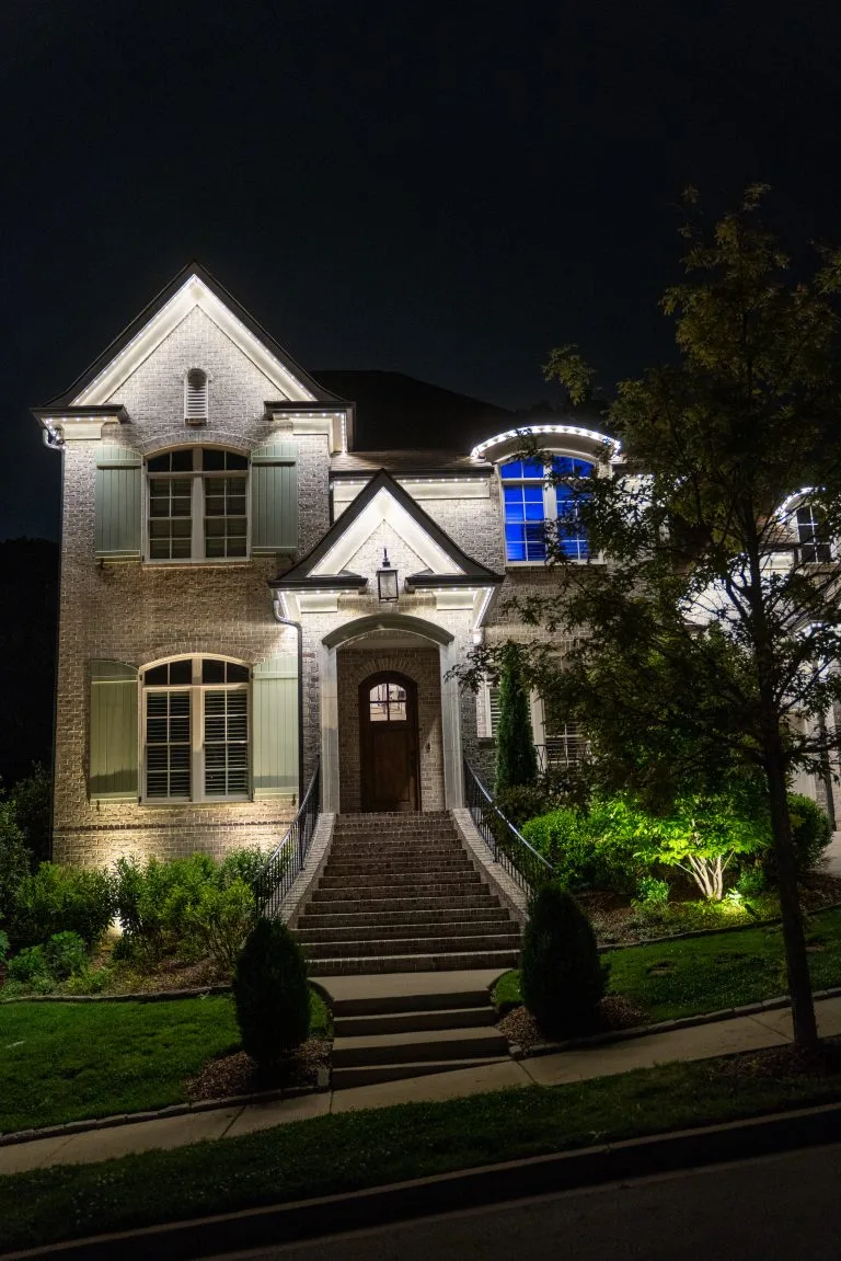 A beautifully lit house glows warmly against a dark night sky