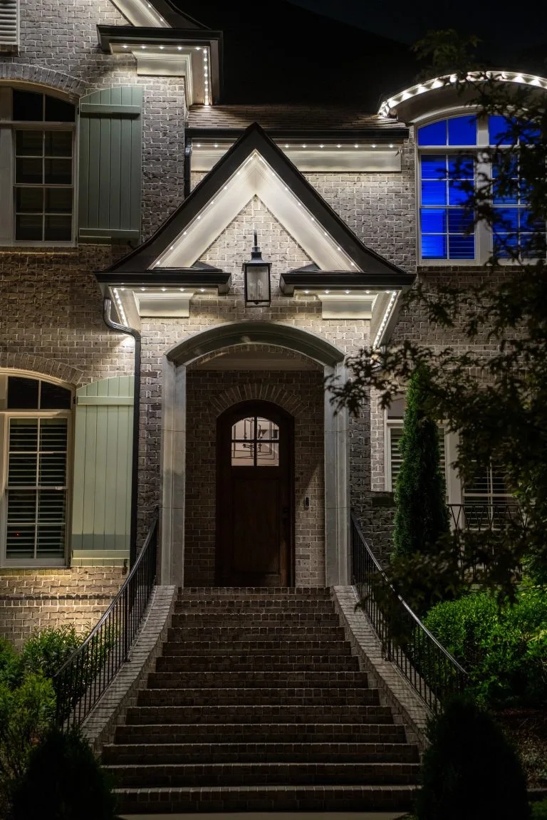 A beautifully lit entrance boasts elegant architecture amidst a dark, nighttime setting