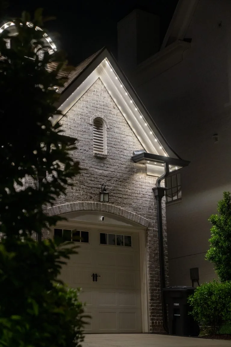 A beautifully lit brick house corner contrasts against the night sky