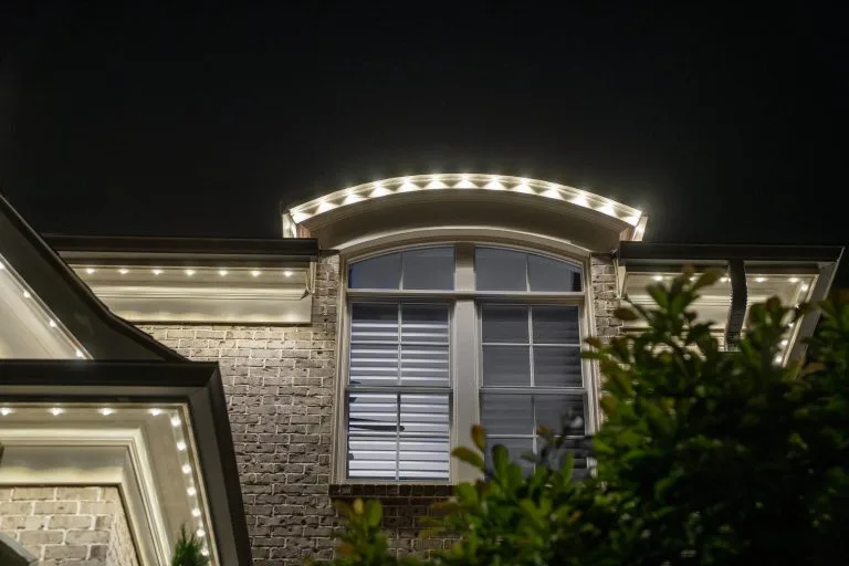 A stylish house is illuminated by warm lights along the eaves