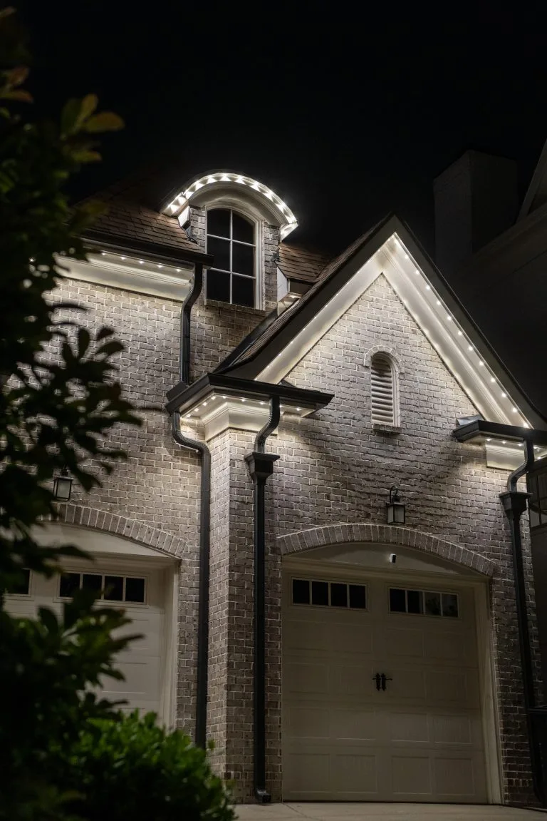 Warm lights illuminate a stylish brick house at night, highlighting its architectural details