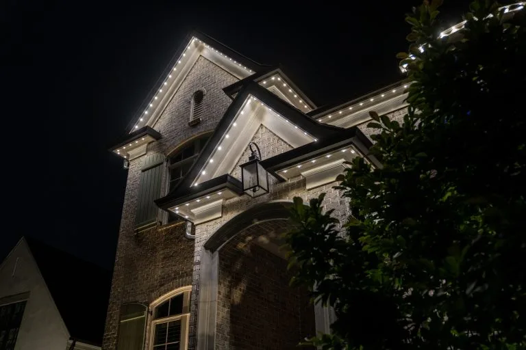 A beautifully lit house shines against the dark night sky