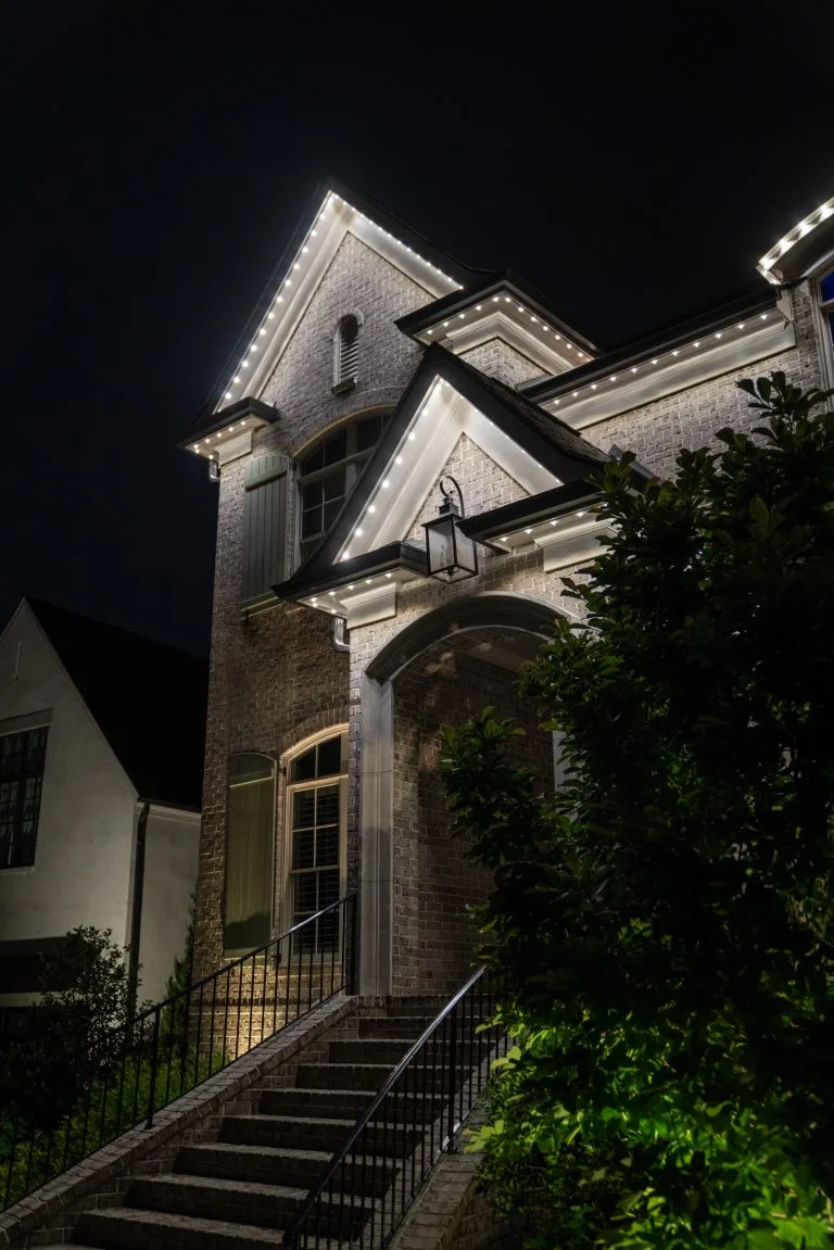 A well-lit, elegant house shines against a dark night sky