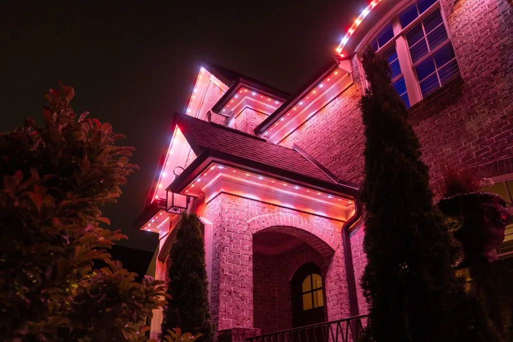 Soffit & under-eave lighting near West End Atlanta illuminates a house with vibrant pink and red lights at night