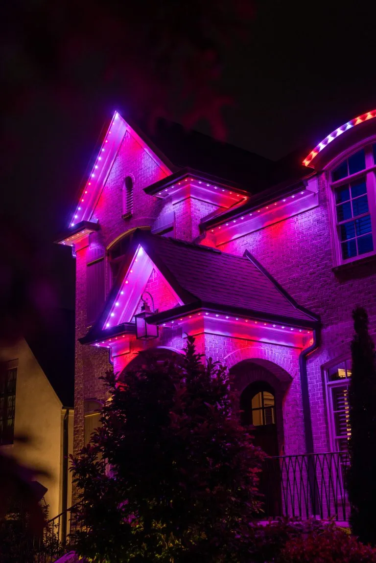 A house is illuminated with vibrant pink and purple lights at night