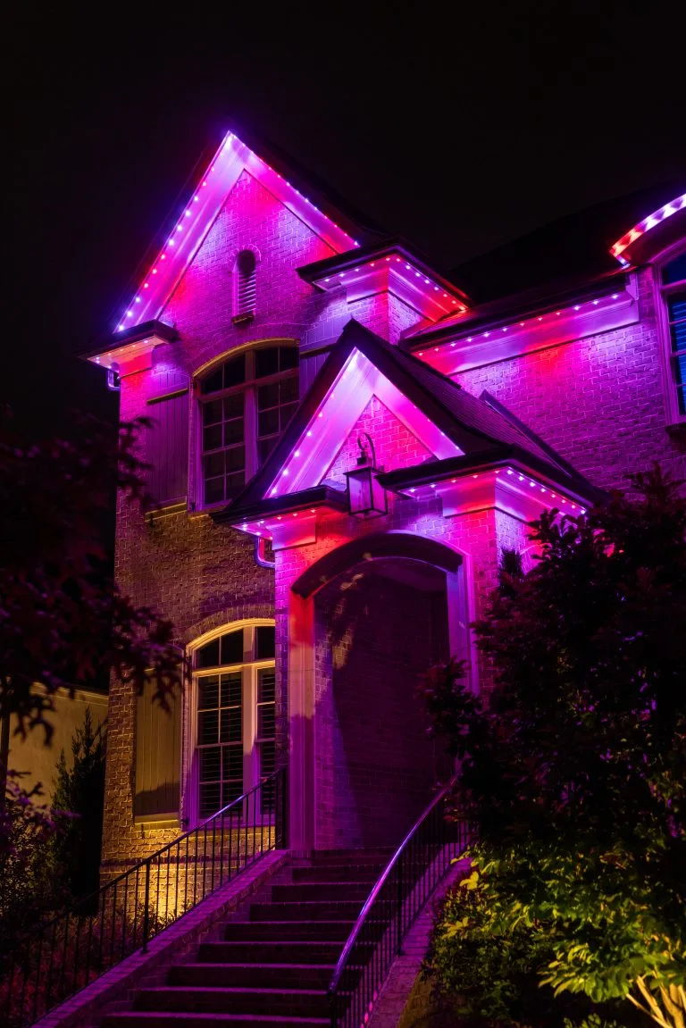 A house is illuminated with vibrant pink and purple lights at night