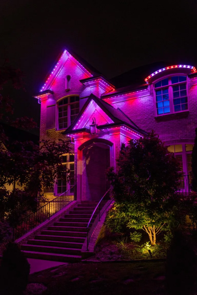 A beautifully illuminated house displays vibrant purple and pink lights at night