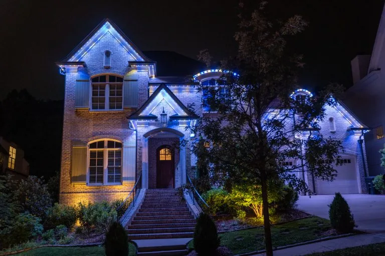 A beautifully illuminated house features blue and warm lighting against a night backdrop