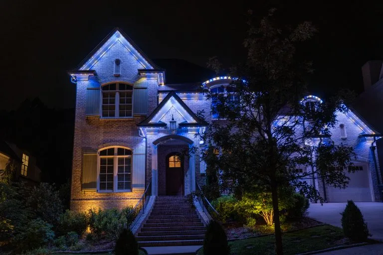 A beautifully illuminated house glows with blue and warm lights at night