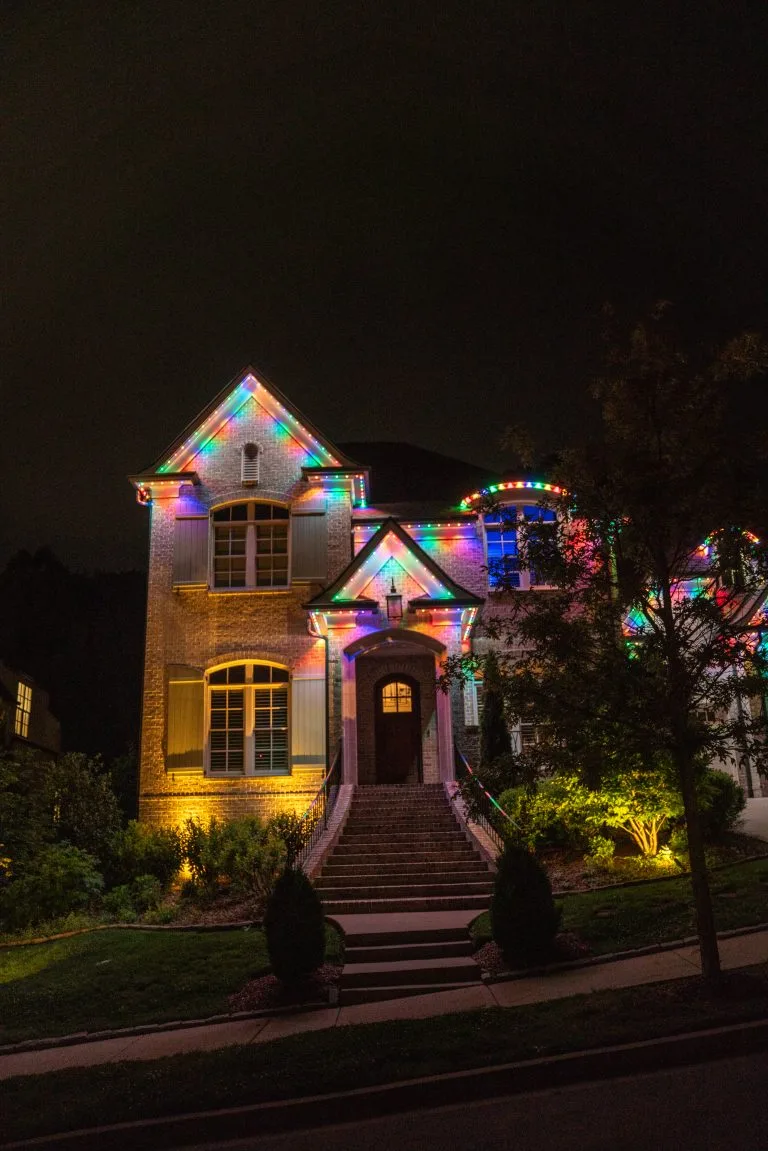 A stylish house is adorned with colorful lights, illuminating the night