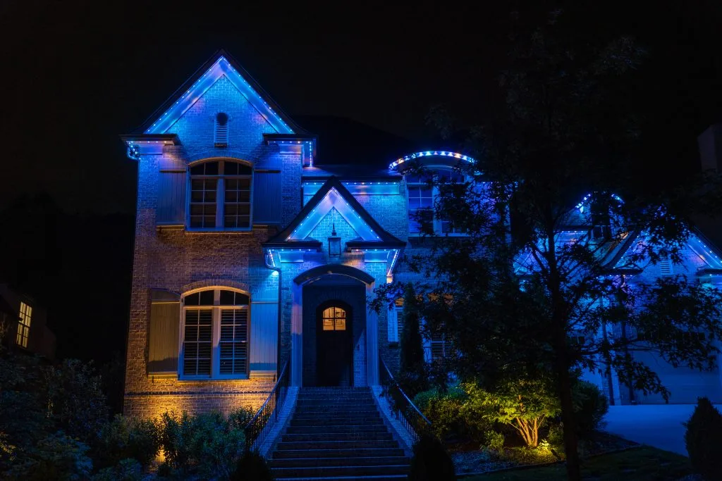 Gemstone lights near Sylvan Park, Tennessee, illuminate a house in vibrant blue against the night sky