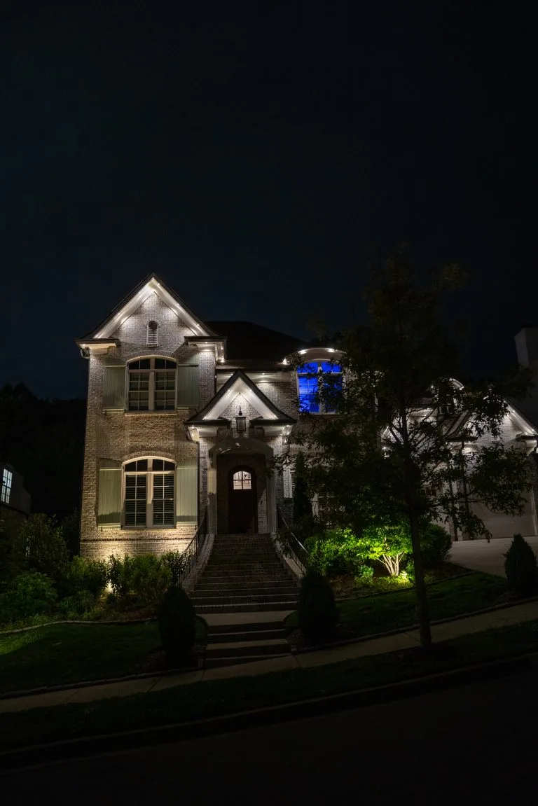 A beautifully lit house stands out against the night sky, highlighting its architectural details