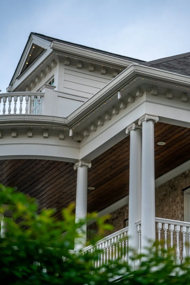 A beautifully detailed home features elegant columns and a decorative balcony under a cloudy sky